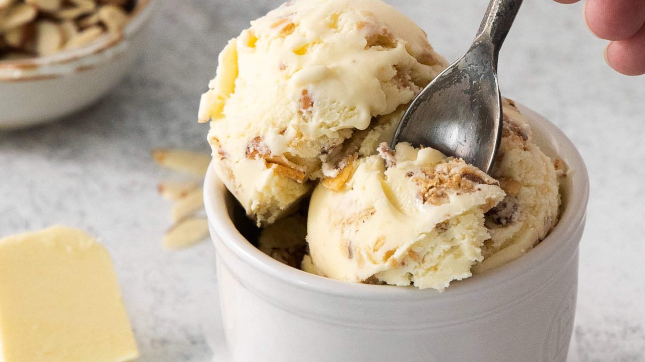 A spoon scooping some Butter Almond Ice Cream out of a dessert cup