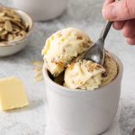 A spoon scooping some Butter Almond Ice Cream out of a dessert cup